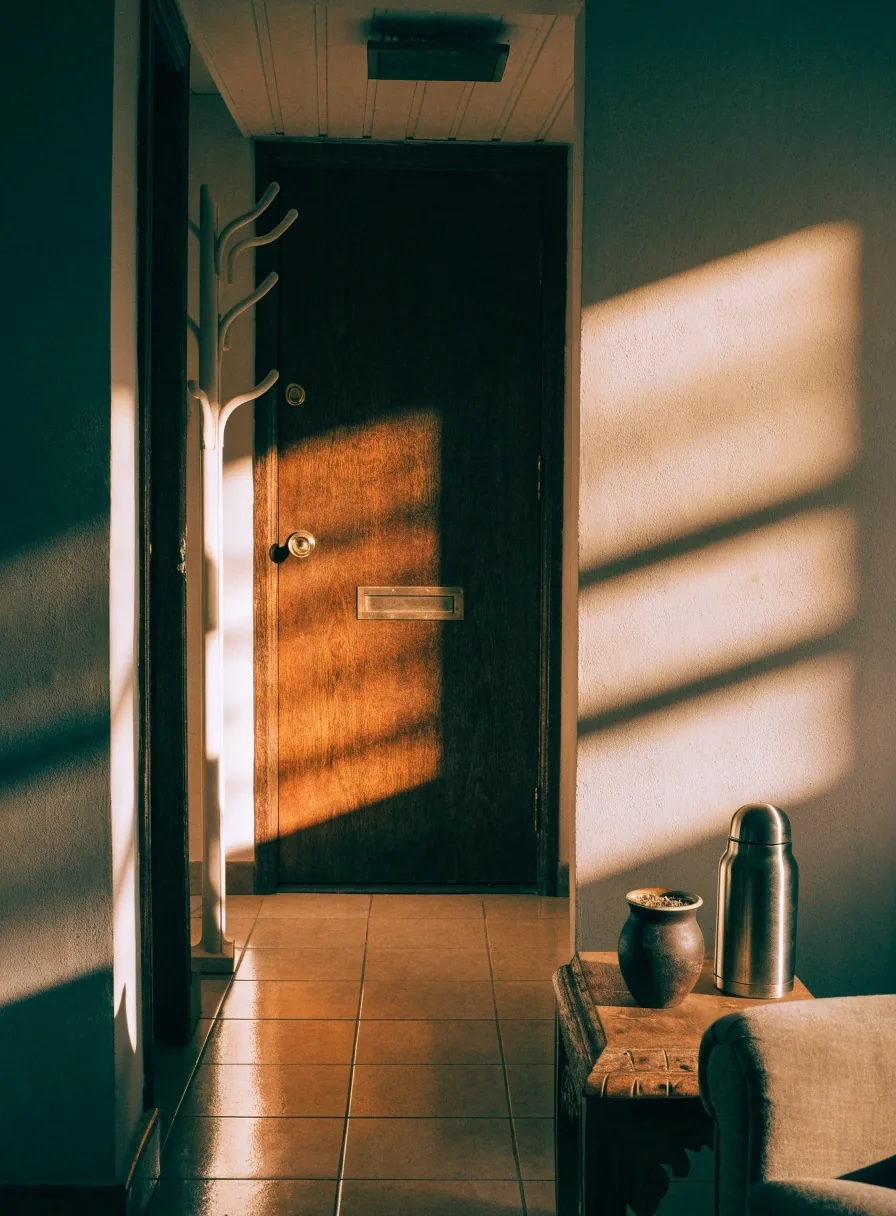 Puerta de entrada de una casa argentina con luz de tarde y un mate sobre la mesa del recibidor